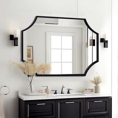 a bathroom with a large mirror above the sink and a vase on the counter next to it