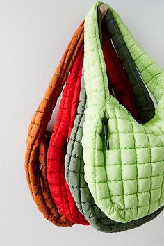 four purses are hanging on the wall in different colors and sizes, one is orange, one is green