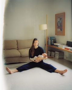 a woman sitting on the floor holding a baby