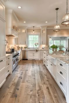 a large kitchen with white cabinets and wood floors