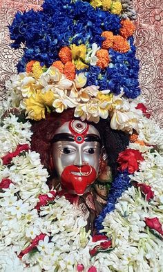 a mask with flowers around it is surrounded by white and red flowers on the ground