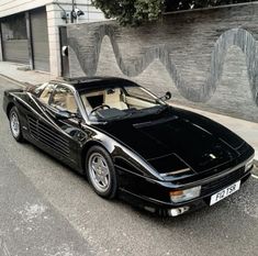 a black sports car parked in front of a building on the side of the road