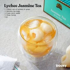 a glass filled with ice and some type of drink on top of a table next to a box