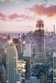 the empire building in new york city is lit up with red and white lights at sunset