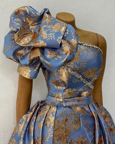 a mannequin wearing a blue and gold dress with flowers on the bustle