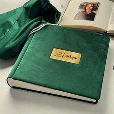 an open book with a name tag on it next to a green bag and other items