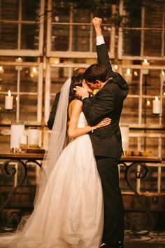 a bride and groom kissing in front of an old building with candles on the windows