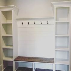 an empty room with some white shelves and black tile on the floor in front of it