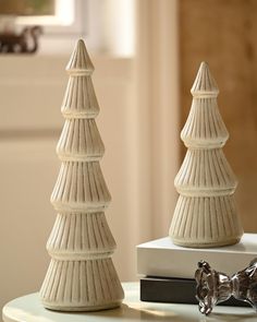 two white ceramic christmas trees sitting on top of a table next to eachother