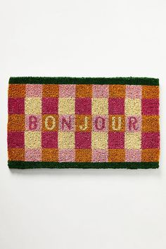 a door mat with the word bonjou on it in pink, yellow and green