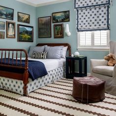 a bedroom decorated in blue and brown with pictures on the wall above the bed, chair, ottoman and window