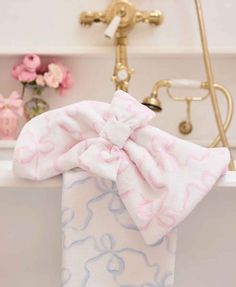 a pink and blue bow tie sitting on top of a bath tub next to a faucet