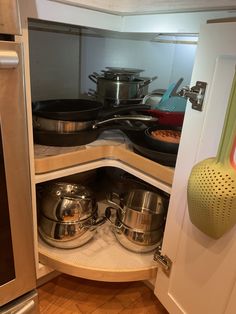 pots and pans are stored in the corner of this kitchen cabinet, which is open