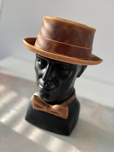 Add a touch of vintage style to your outfit with this handmade pork pie hat and bow tie set, crafted from genuine Crazy Horse leather.  This set is perfect for: - Special occasions such as weddings, proms, and formal events - Adding a touch of sophistication to your everyday look - A unique and thoughtful gift for the man in your life HAT SIZE: We will sew a hat, especially for you, according to the size of your head. How to know your size? Measurements should be made directly above the ears - this will be a conditional line of the landing of your hat.  Repeat the measurement several times - around the widest part of the head.  The head circumference in centimeters will be the size of your hat. BOW TIE SIZE: 4,7 x 2.4 inch (12cm x 6cm) The bow tie has an adjustable strap for a comfortable Classic Brown Top Hat For Kentucky Derby, Classic Brown Top Hat For Formal Occasions, Classic Brown Formal Top Hat, Adjustable Brown Top Hat For Kentucky Derby, Formal Brown Brimmed Top Hat, Fitted Brown Boater Hat With Flat Crown, Handmade Vintage High Crown Top Hat, Classic Brown Handmade Hat, Formal Adjustable Top Hat With Flat Bill