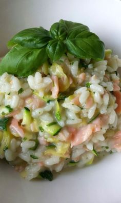 a white bowl filled with rice and vegetables on top of a green leafy garnish