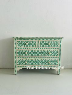 an ornate green and white dresser with drawers