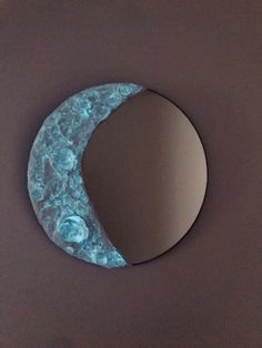 a circular mirror sitting on top of a table next to a moon shaped wall hanging