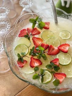 a glass bowl filled with lemon, strawberries and lime slices