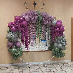 an arch made out of balloons in the shape of flowers is displayed on a wall