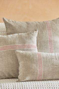 two pillows sitting on top of a bed next to a pillow case with red and white stripes