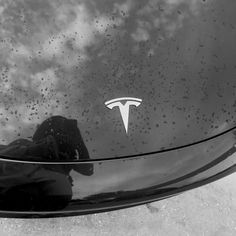 the hood of a car with a tesla logo on it's side window and clouds in the background