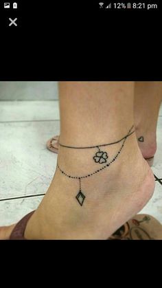 a woman's foot with a chain and flower tattoo on the bottom of her ankle