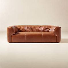 a brown leather couch sitting on top of a white floor