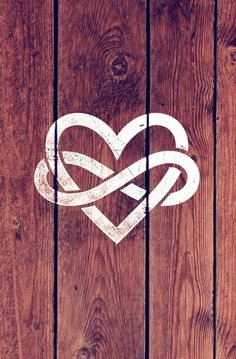 a heart with two intertwined hearts painted on the side of a wooden fence,