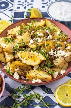 a bowl filled with potatoes covered in feta cheese and garnished with herbs