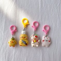 four keychains with various cartoon characters attached to them on a white sheeted surface