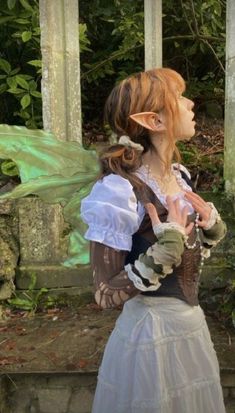 a woman dressed as a fairy standing in front of some pillars