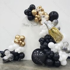 black, white and gold balloon arch with champagne bottle