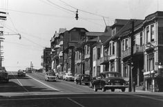 an old black and white photo of cars driving down the street