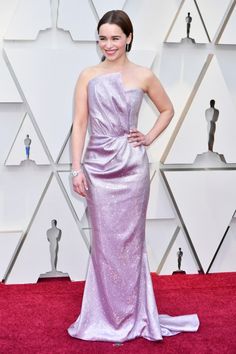 a woman in a purple gown on the red carpet at an oscars event with her hands on her hips