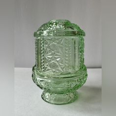 a green glass jar sitting on top of a table