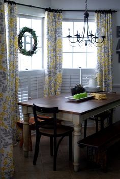 a dining room table and chairs with yellow curtains