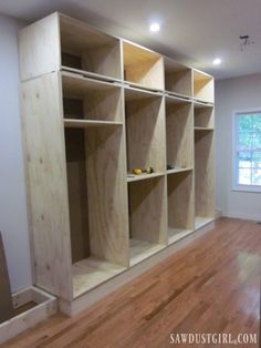 an empty room with wooden shelves in the middle and hard wood flooring on the other side