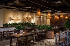 an empty restaurant with wooden tables and planters on the wall, along with potted plants