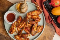 chicken wings on a plate with ketchup and oranges in the background,