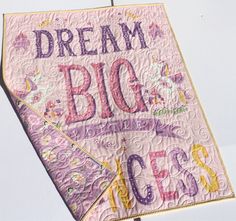 a pink quilt with the words dream big written in purple and yellow letters on it