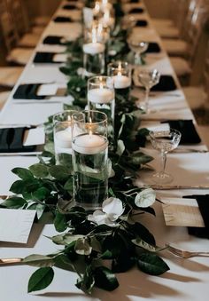 a long table with candles and greenery on it