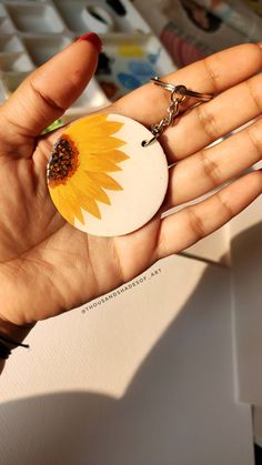 a hand holding a key chain with a sunflower on it