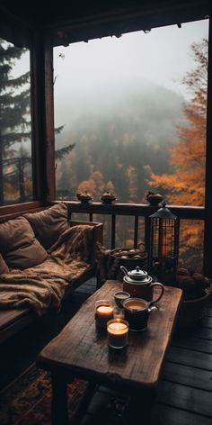 two candles are sitting on a coffee table in front of a window overlooking the mountains