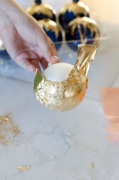 a person holding an egg in their hand with gold foil on it and other decorations