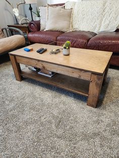 a wooden table sitting on top of a carpeted floor next to a brown couch