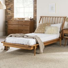 a wooden bed with white sheets and pillows