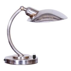 a metal desk lamp on a white background with clippings to the side and one light turned on