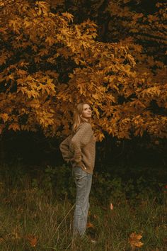 a woman standing in front of a tree with yellow leaves