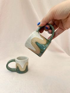 a person is holding a mug in their hand