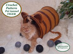 an orange cat is sitting in a crochet pet tunnel with balls around it